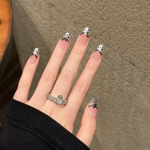 French press-on nails with silver glitter tips, black bows, and polka dots on nude base