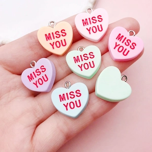 Colorful resin heart pendants with Miss You lettering and metal rings in hand display