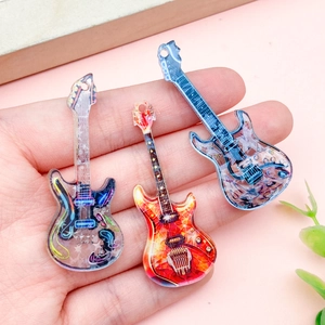 Acryl-Gitarrenanhänger in verschiedenen Farben auf der Hand mit rosa Hintergrund