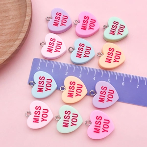 Macro shot of colorful resin heart charms with MISS YOU text and silver rings for DIY jewelry