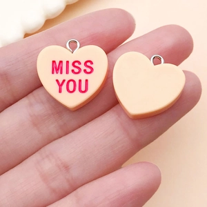 Detail of pink resin heart pendants with Miss You engraving for DIY jewelry making