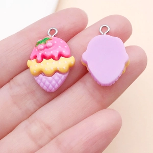 Detail of a pink and yellow resin ice cream charm held by hand for size reference