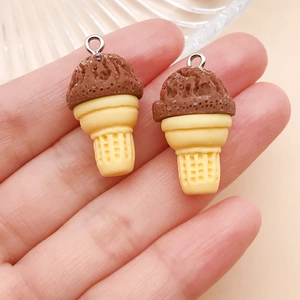 Close-up of resin chocolate ice cream cone charms with silver metal rings held in hand