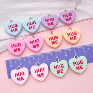 Gros plan de breloques cœur en résine avec texte Hug Me pour bijoux DIY et artisanat