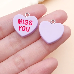 Macro view of lavender heart charms with Miss You text and silver metal link rings