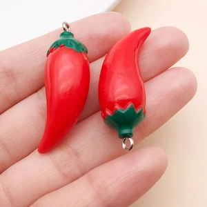 Close-up of red chili resin pendants with silver metal rings for DIY jewelry making