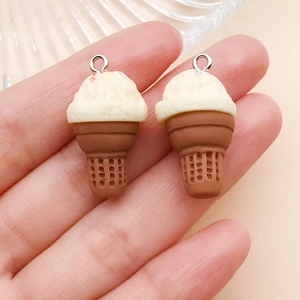Close-up of resin ice cream cone charms with silver metal rings held in hand for scale