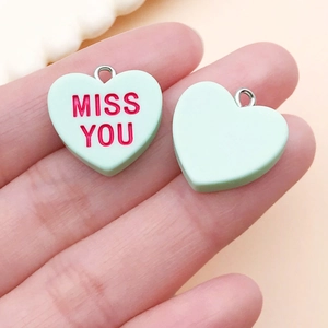 Detailed view of mint green heart charms with Miss You text for DIY jewelry making