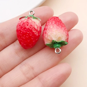 Detail of strawberry-shaped resin pendants with red gradient finish and metal loops