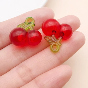 Macro shot of two translucent red resin cherry charms with green leaves for DIY jewelry