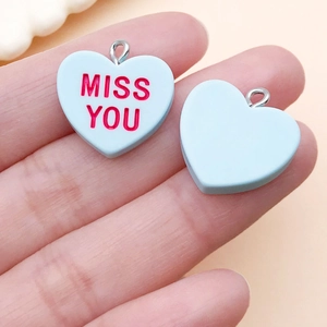 Close-up of light blue resin heart pendants with red Miss You text for DIY jewelry