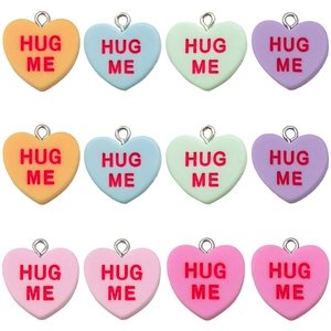 Pendentifs cœur en résine colorée avec lettres Hug Me disposés en grille sur blanc