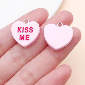 Detail von rosa Herz-Anhängern aus Harz mit Kiss Me Text und silbernen Metallringen