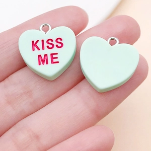 Detail eines minzgrünen herzförmigen Harzanhängers mit rotem KISS ME Schriftzug