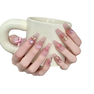 Handmade press-on nails in pink gradient with golden butterfly and bow accents