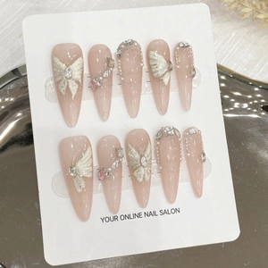 Unghie finte stiletto fatte a mano in rosa nudo con farfalle 3D e dettagli di perle
