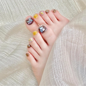 Handmade press-on toenails featuring brown shell patterns and yellow glitter accents