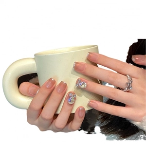 Faux ongles nude dégradé style français avec nœuds argentés et strass brillants