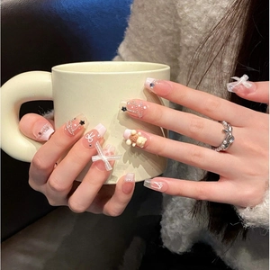 Handmade press-on nails with pink French tips, white bows, pearls, and 3D bear charms