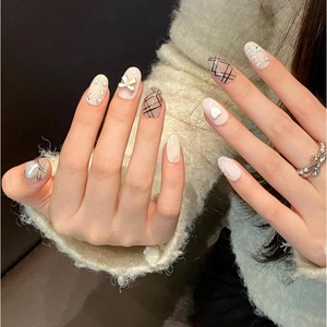Handmade press-on nails featuring elegant bows, pearls, and heart patterns in nude pink tones