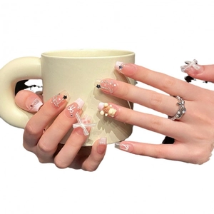 Pink and white press-on nails with 3D bears, silk bows, and pearls in a French chic style