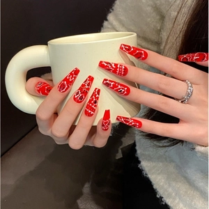 Faux ongles longs forme cercueil rouges avec motifs paisley blancs portés