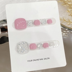Handmade press-on toenails in pink and silver glitter design on a display board