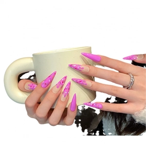 Handmade stiletto press-on nails with pink candy drip design on a ceramic cup