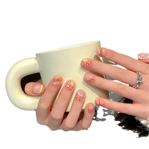 Short round press-on nails with fresh lemon fruit slices and colorful dots on pink base