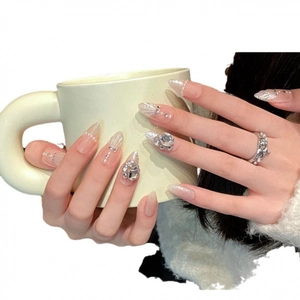 Unghie finte stiletto lunghe con sfumatura rosa nude, glitter e decorazioni strass