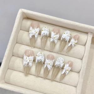 Faux ongles faits main avec relief 3D blanc et perles sur forme amande longue élégante