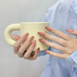 Faux ongles faits main en œil de chat brun-rouge de forme amande sur fond lifestyle