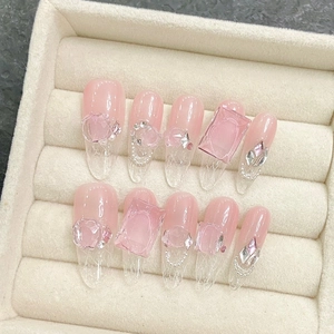 Pink translucent press-on nails with ice-glaze gems and silver chains in a jewelry box