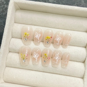 Faux ongles faits main avec motifs floraux, perles et strass en rose poudré