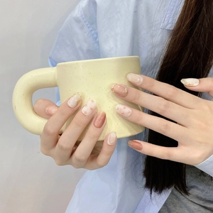 Handmade light pink press-on nails with 3D dots and gold foil on a yellow mug