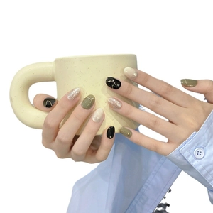 Minimalist olive green and gold press-on nails set shown on hands holding a mug