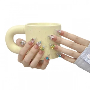 Handmade gradient press-on nails with colorful rhinestones and pearls on a white background