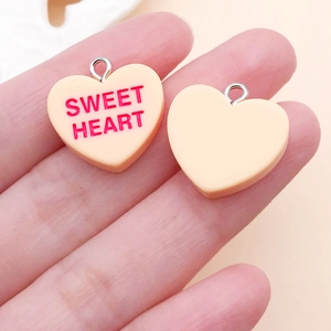 Detail of pink heart pendants with Sweet Heart text and silver loops for DIY crafts