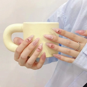 Pink gradient almond press-on nails with petal textures and small gold crescent accents