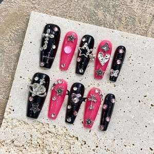 Handmade Y2K press-on nails set with 3D metal charms and pink rhinestones on stone background