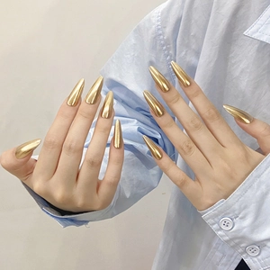 Glossy golden mirror finish stiletto press-on nails shown on hands with modern style