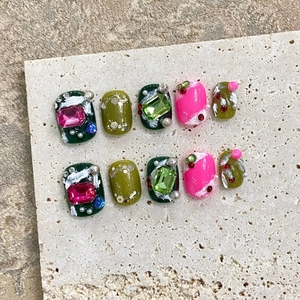 Handmade press-on nails set with green and pink gemstones and white embossed texture