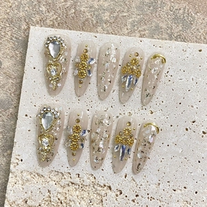 Handmade almond press-on nails with gold foil, rhinestones and sequins on nude base