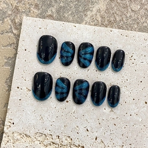 Handmade dark cat eye press-on nails with black oval shape and blue shimmer French tips