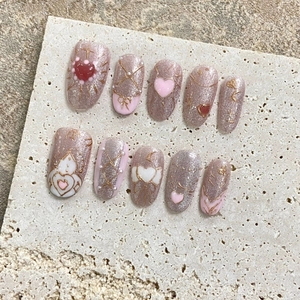 Pink cat eye press-on nails with 3D heart, pearl, and gold ribbon decorations