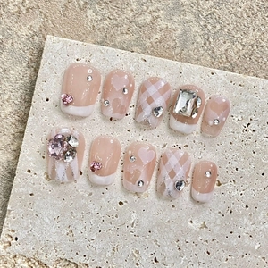 Faux ongles rose avec cœurs et pointes French blanches ornés de strass de luxe