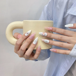 Pink and white gradient press-on nails with 3D floral and heart charms on long almond shape