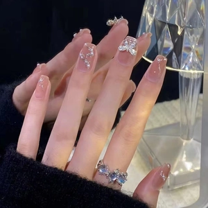 Vue détaillée des ongles dégradés nude avec papillon en zircon 3D et perles fines