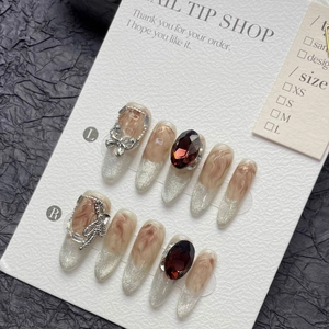Handmade amber cat-eye press-on nails with silver bows and large oval red gemstones