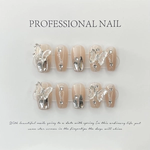 Handgemaakte nude press-on nagels met 3D-vlinderbedeltjes en zilveren glitters